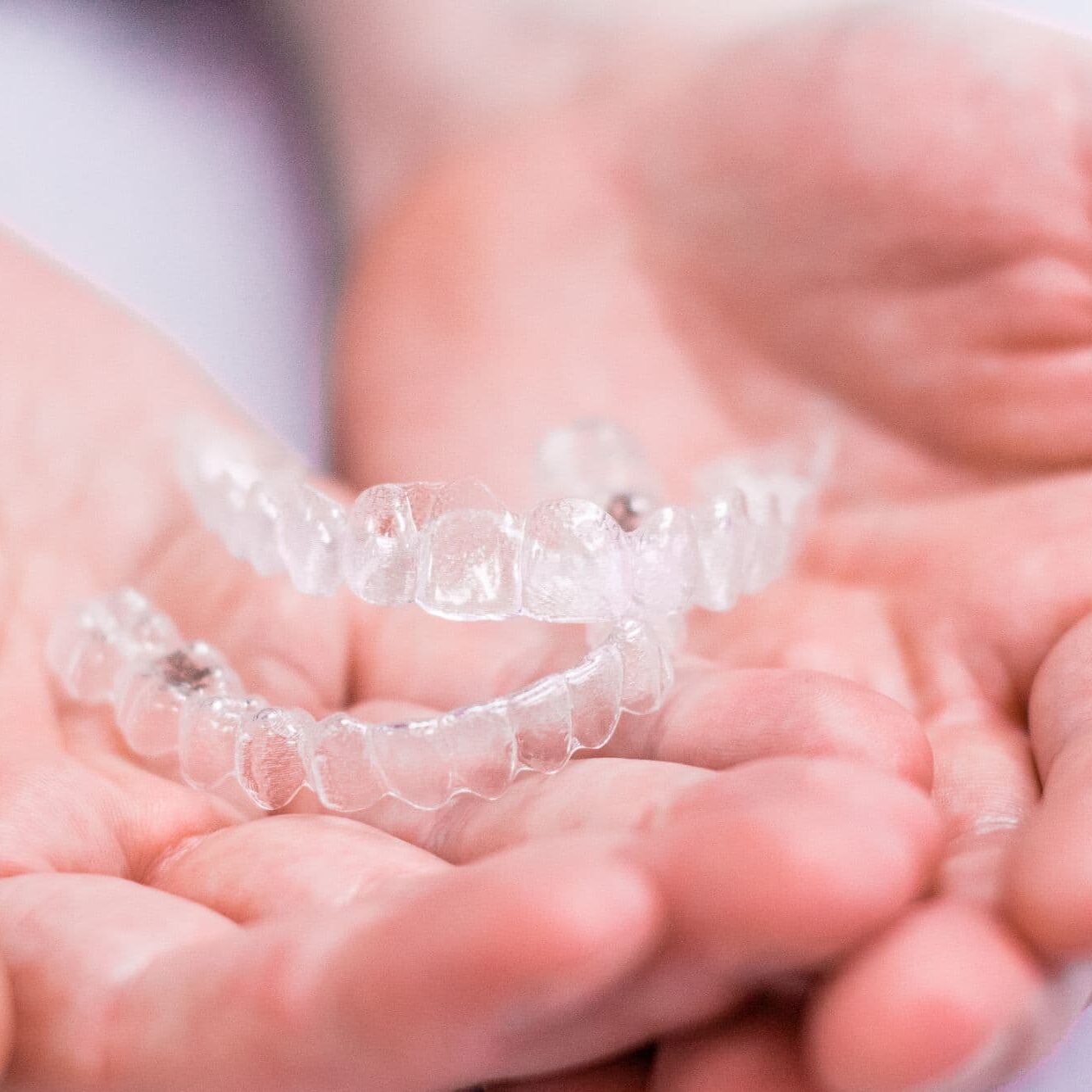 hands holding Invisalign aligners